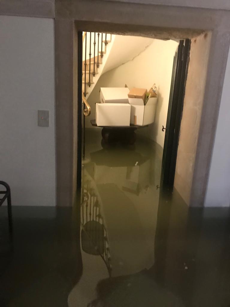 La base della scala ovoidale con scatole di oggetti che sono riuscito a mettere in salvo sul tavolo non sommerso